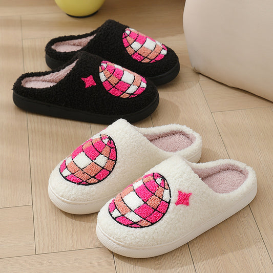 Pair of black and white slippers with disco ball design on a wooden floor.