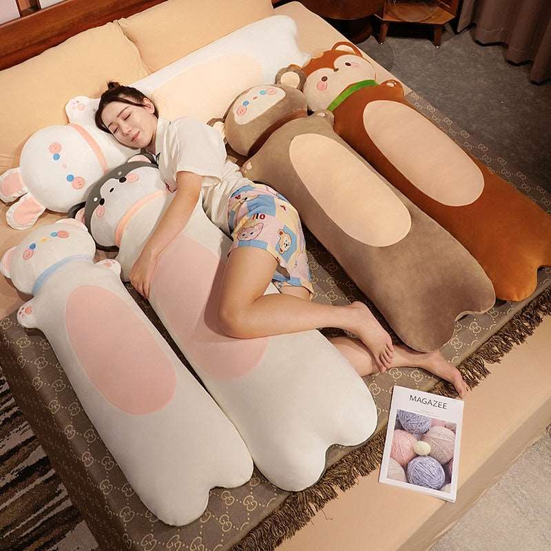 Long snuggle buddy plush pillows in a variety of cartoon animal designs, shown on a cozy bed.