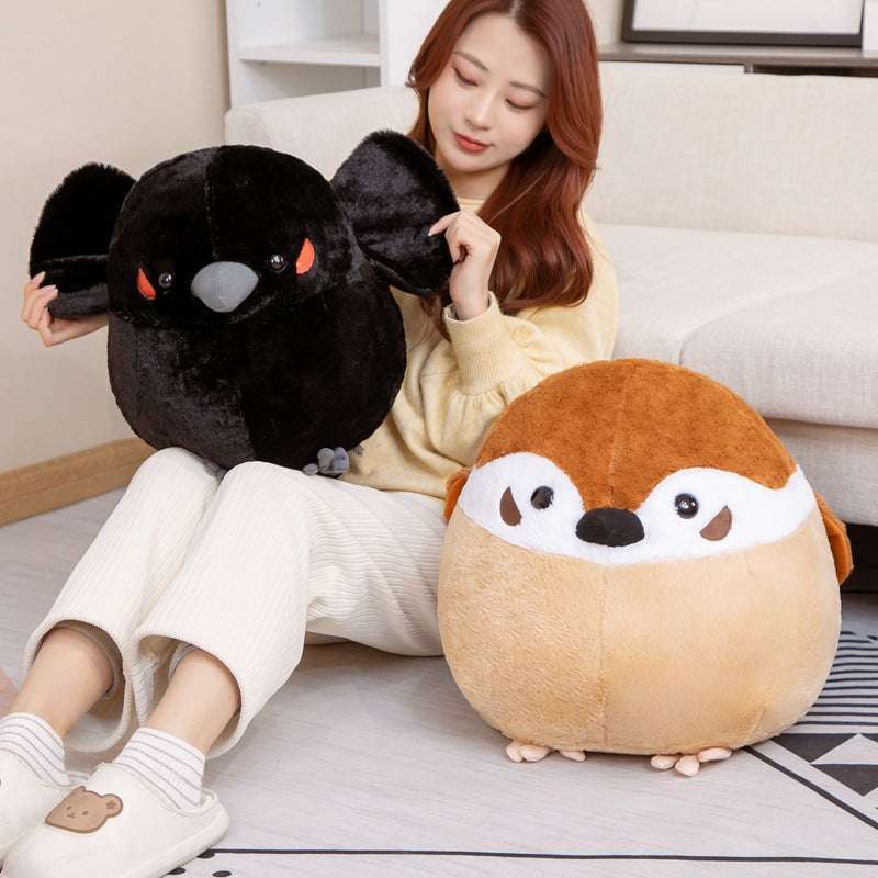 Person holding brown sparrow and black crow plush toys